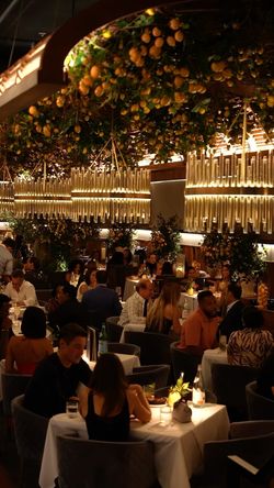 Elegant interior of Sparrow Italia Miami featuring modern chandeliers, lemon decorations, and diners enjoying a cozy ambiance