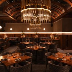 Sparrow Italia Miami interior with wooden tables, velvet chairs, and modern chandeliers creating a warm atmosphere.
