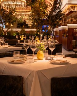 Elegant restaurant table setting with glasses, plates, and a centerpiece, featuring warm lighting and intimate ambiance.