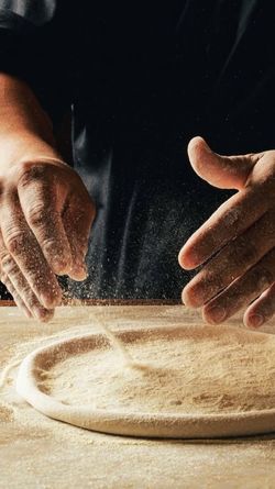 Hands dusting flour on a dough base, preparing fresh pasta or pizza at Sparrow Italia Miami.