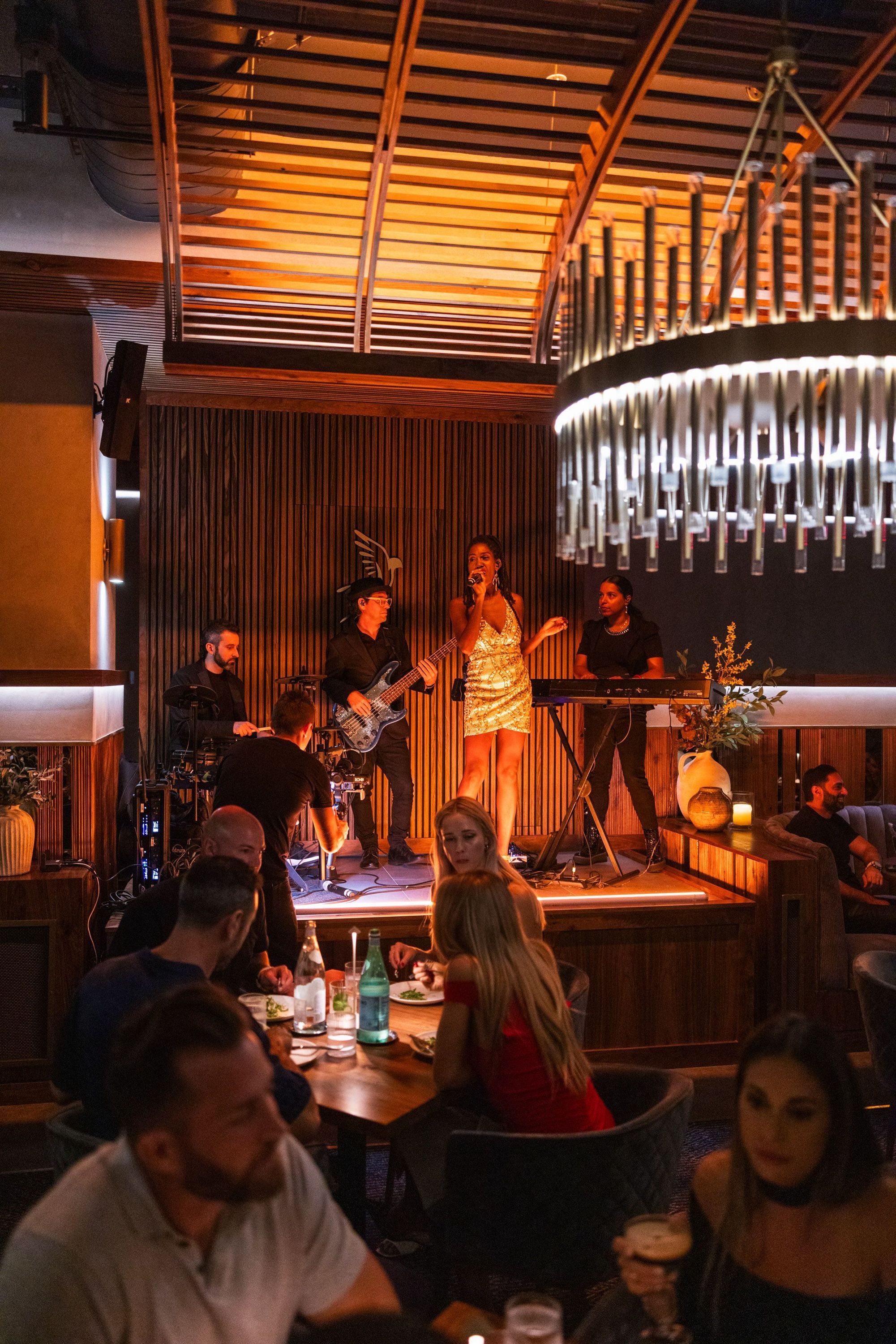 Live music performance on a small stage with guests dining in a warmly lit restaurant interior of Sparrow Italia Miami.